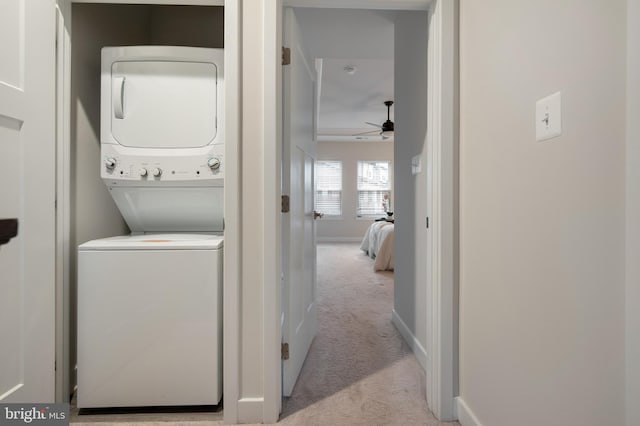 laundry room with light carpet, laundry area, baseboards, ceiling fan, and stacked washing maching and dryer