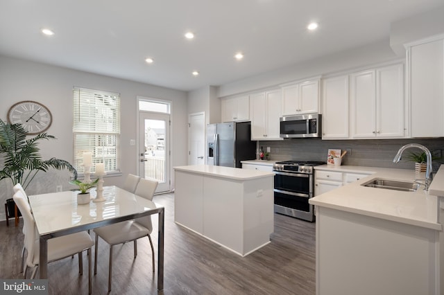 kitchen featuring decorative backsplash, a kitchen island, dark wood-style flooring, stainless steel appliances, and a sink