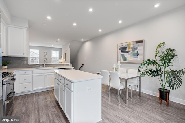 kitchen with light wood-style floors, a kitchen island, range with two ovens, and a sink