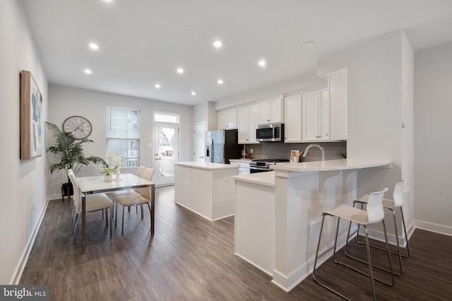 kitchen featuring a center island, dark wood finished floors, light countertops, decorative backsplash, and appliances with stainless steel finishes