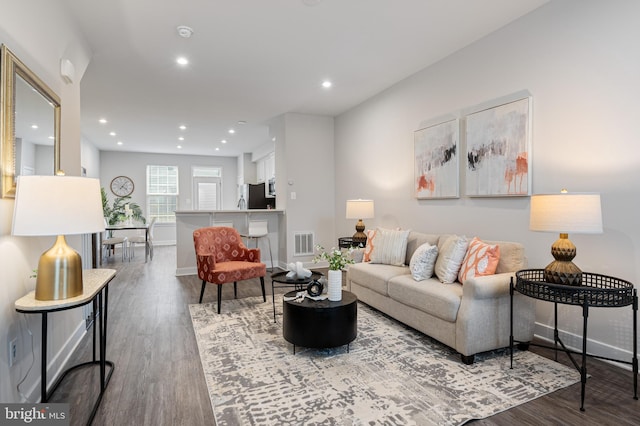 living area with baseboards, visible vents, wood finished floors, and recessed lighting