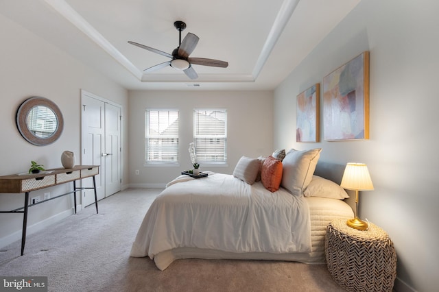 bedroom featuring a tray ceiling, visible vents, a ceiling fan, carpet flooring, and baseboards