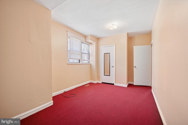 carpeted spare room featuring baseboards