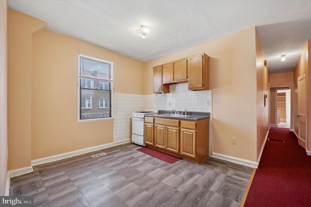 kitchen with dark countertops, visible vents, white range with gas stovetop, tile patterned floors, and a sink