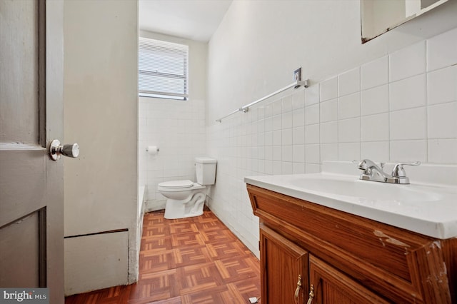 half bathroom with toilet, tile walls, and vanity