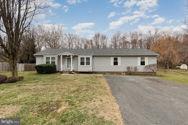 ranch-style house featuring a front lawn, fence, and roof with shingles