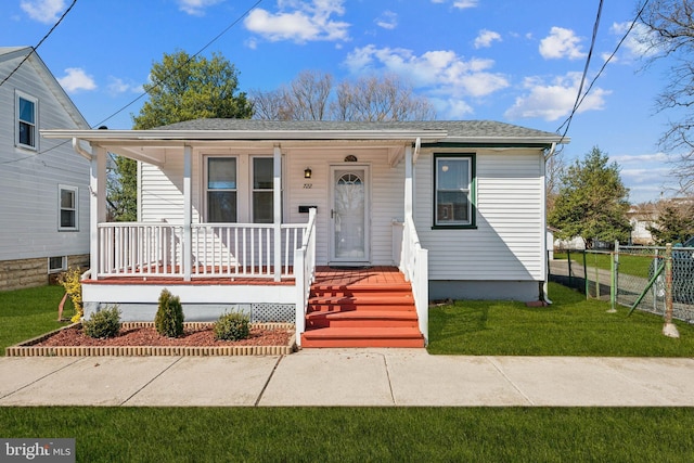 bungalow-style house featuring a porch, a shingled roof, a front yard, and fence