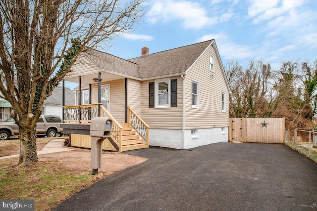 view of front of home featuring a shingled roof, a chimney, a gate, and fence