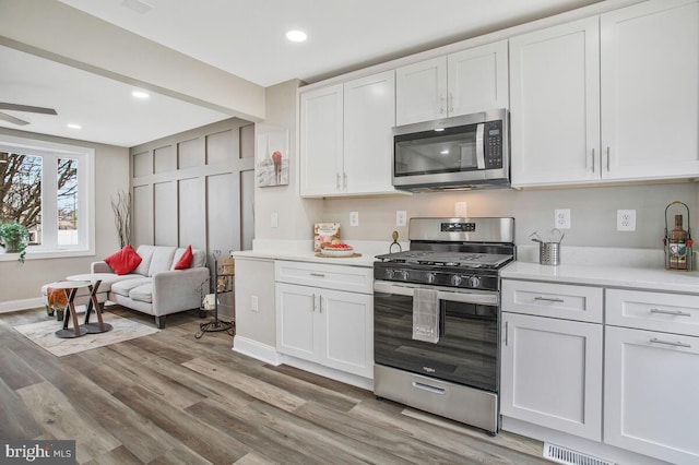 kitchen with recessed lighting, white cabinetry, light wood-style floors, light countertops, and appliances with stainless steel finishes