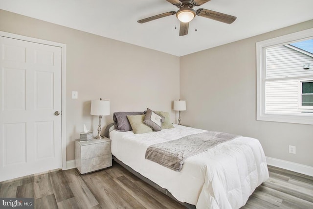 bedroom with ceiling fan, wood finished floors, and baseboards