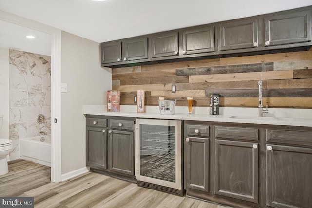 bar featuring light wood-type flooring, beverage cooler, indoor wet bar, and a sink