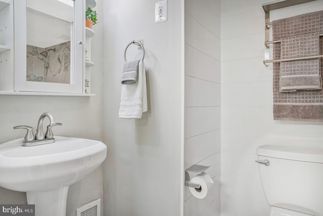 bathroom featuring toilet, a sink, and visible vents