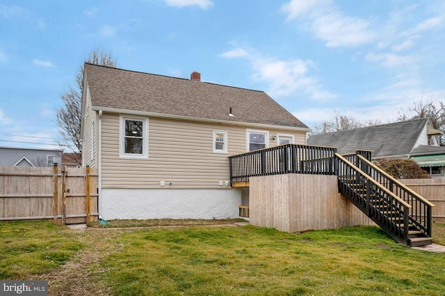 rear view of house with stairs, a shingled roof, a lawn, and fence