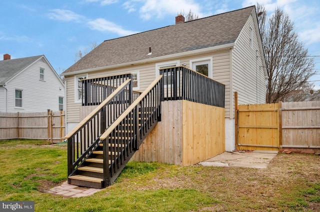 back of house featuring a shingled roof, a fenced backyard, a chimney, stairway, and a yard