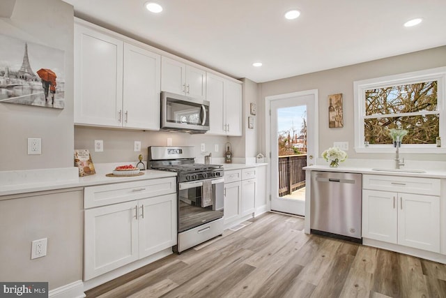 kitchen featuring light wood-style floors, appliances with stainless steel finishes, white cabinets, and light countertops