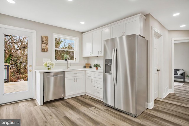 kitchen featuring light wood-style floors, appliances with stainless steel finishes, light countertops, and a sink