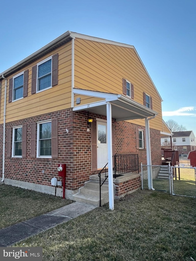 view of front of property with brick siding, a front lawn, and fence