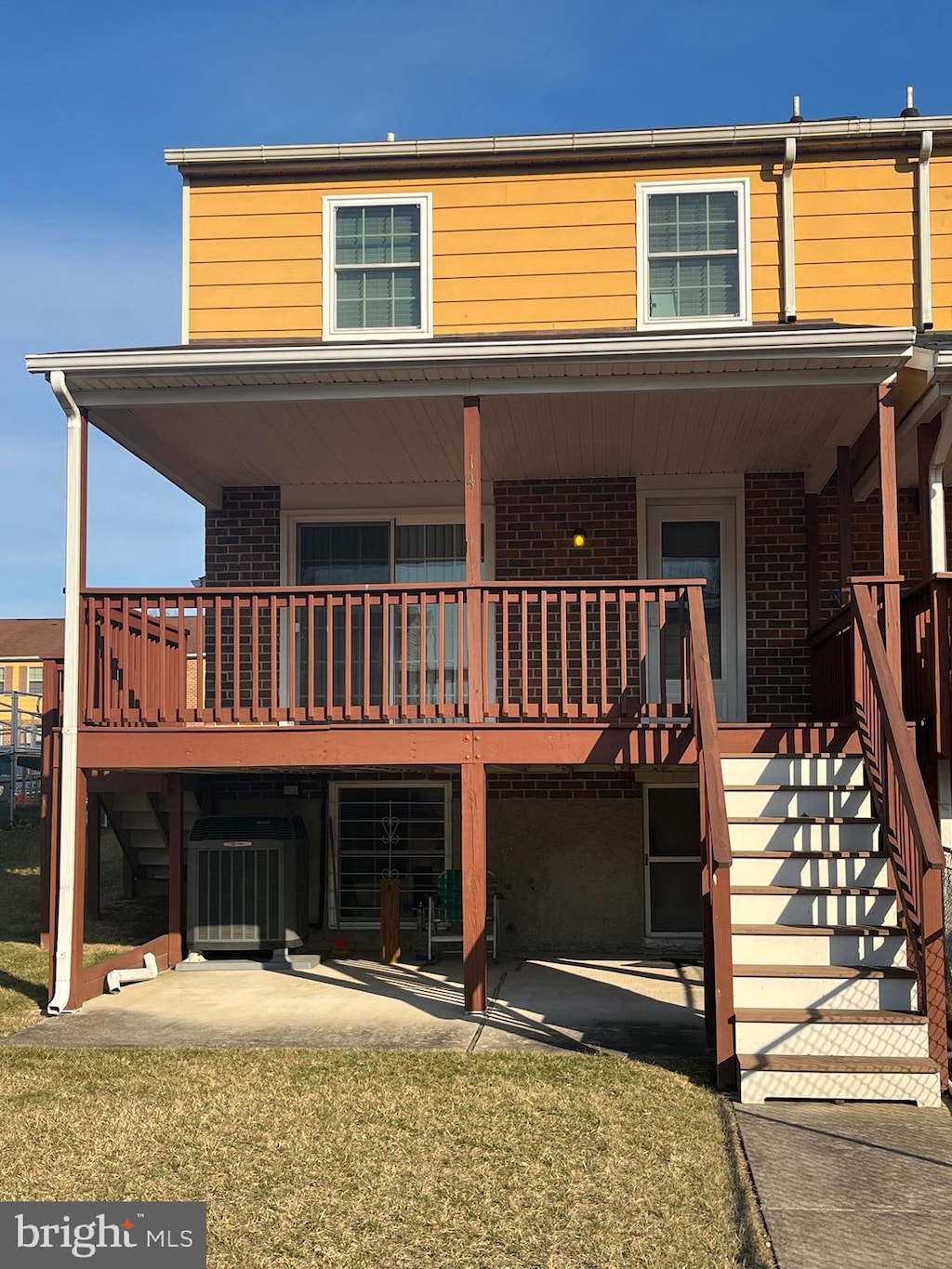 view of front facade with central AC, brick siding, stairway, and a patio area