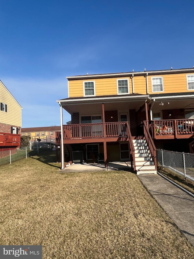 rear view of house with stairway, a yard, and fence