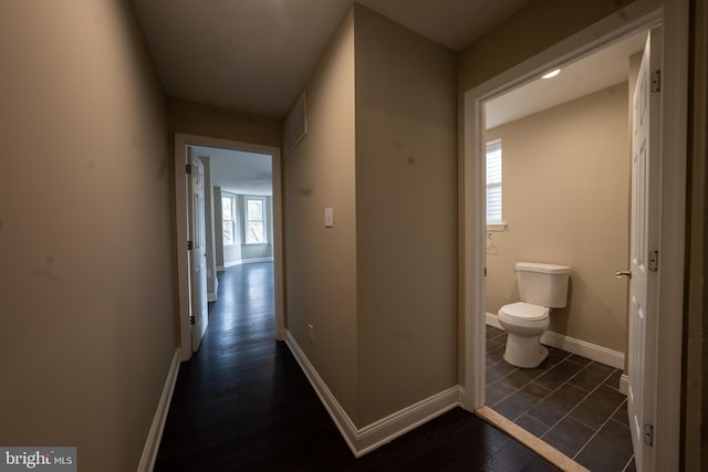 corridor featuring dark wood-style floors and baseboards