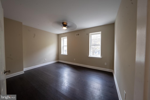 empty room featuring dark wood-style floors, visible vents, baseboards, and a ceiling fan