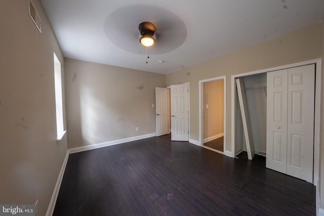 unfurnished bedroom featuring visible vents, baseboards, a ceiling fan, dark wood-type flooring, and a closet