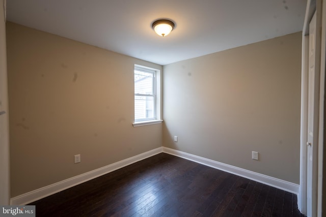 empty room with baseboards and dark wood-style flooring