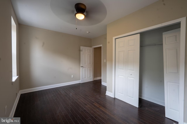 unfurnished bedroom with dark wood-style flooring, a closet, a ceiling fan, and baseboards