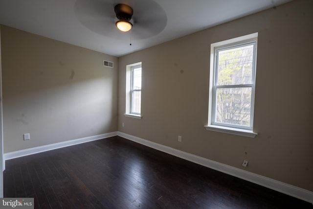 empty room with dark wood-style floors, baseboards, visible vents, and ceiling fan