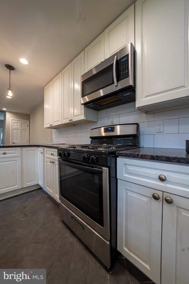 kitchen with white cabinets, tasteful backsplash, stainless steel appliances, and dark stone countertops