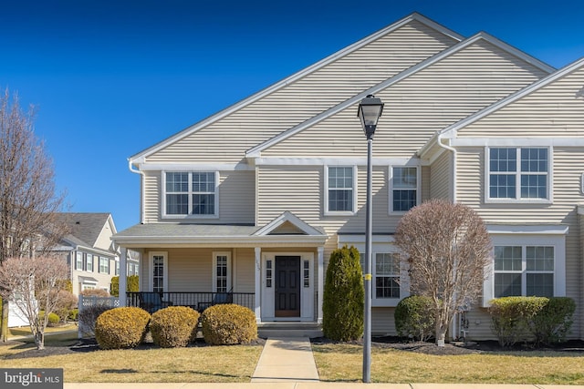 view of property featuring a porch and a front yard