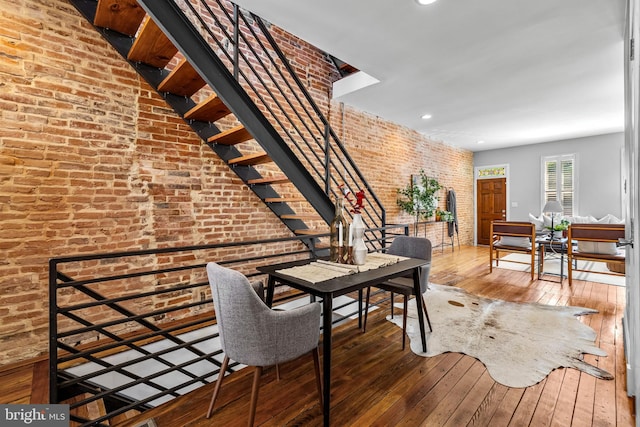 dining room with brick wall, wood-type flooring, stairway, and recessed lighting