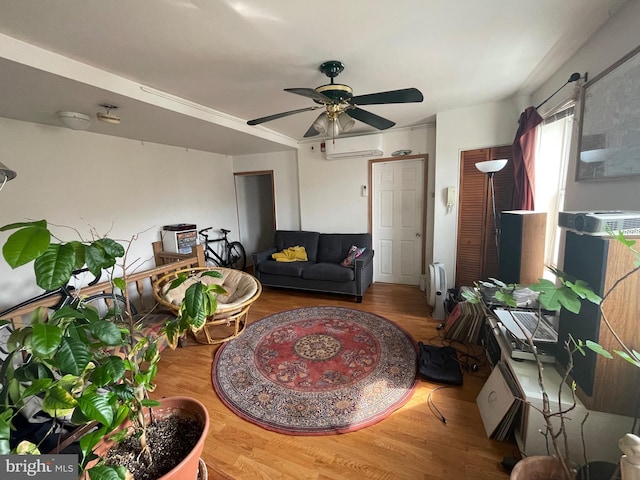 living area featuring ceiling fan, an AC wall unit, and wood finished floors