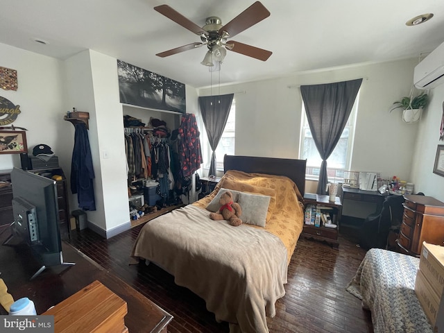 bedroom with a wall mounted air conditioner, a ceiling fan, a closet, and wood-type flooring