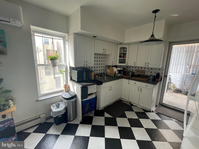 kitchen with white cabinetry, a wall mounted air conditioner, a baseboard heating unit, dark countertops, and dark floors