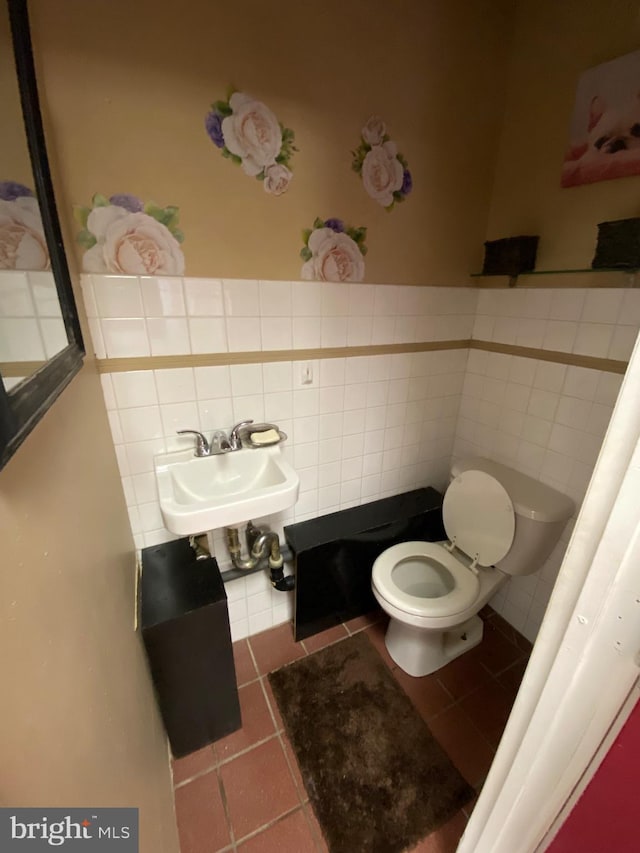 bathroom featuring a sink, tile patterned flooring, wainscoting, tile walls, and toilet