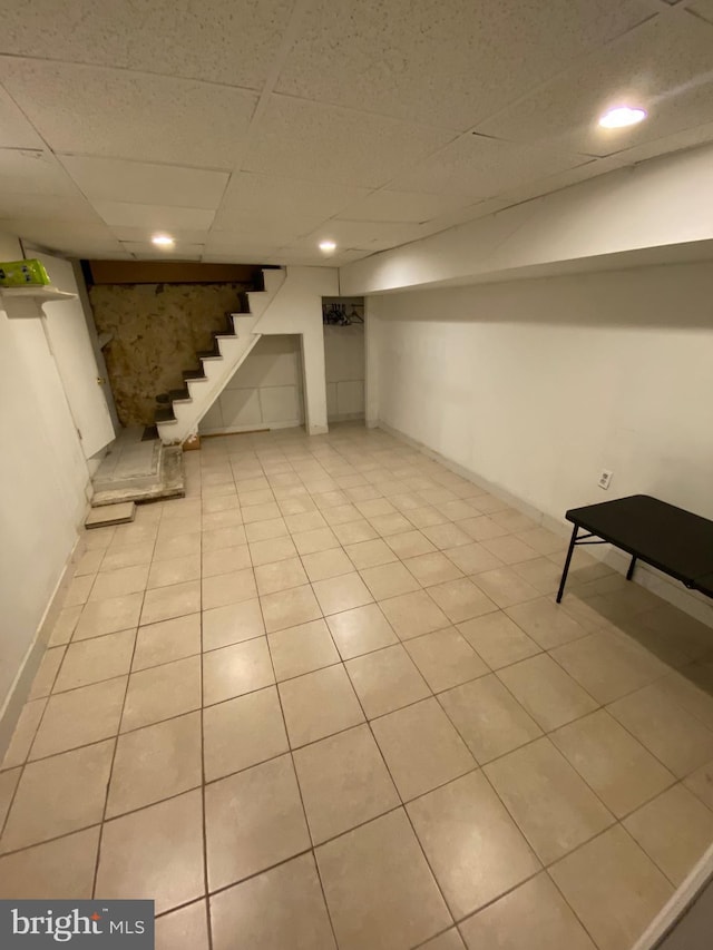 finished basement featuring stairway, baseboards, light tile patterned flooring, recessed lighting, and a paneled ceiling