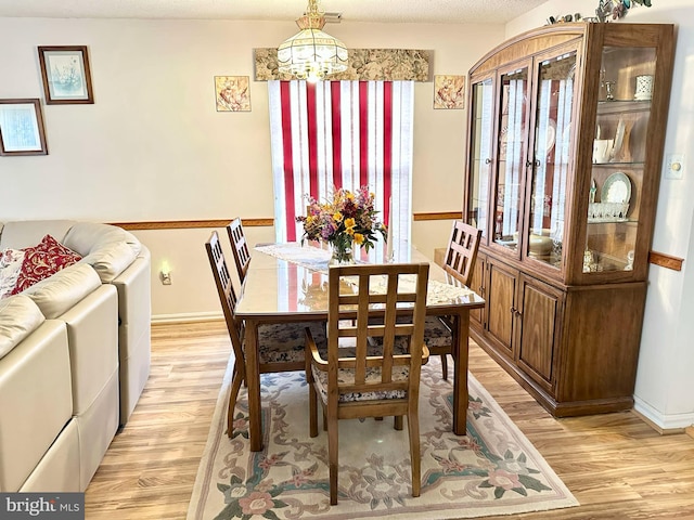 dining space with light wood-type flooring, baseboards, and a chandelier