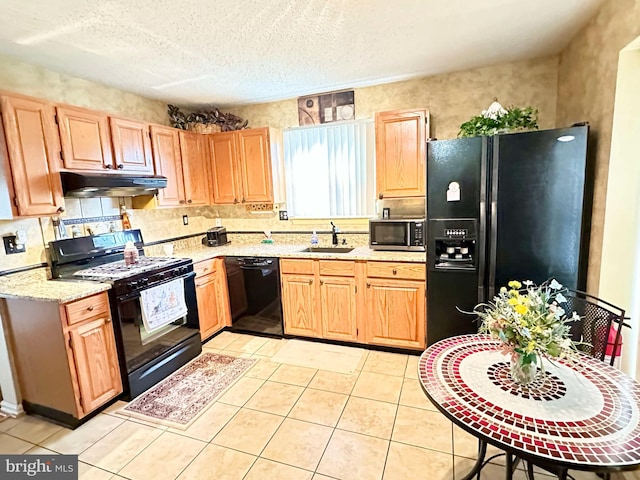 kitchen featuring light brown cabinets, under cabinet range hood, a textured ceiling, black appliances, and a sink