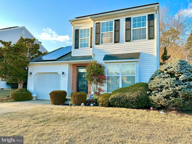 traditional-style house featuring driveway, roof mounted solar panels, a front yard, a garage, and brick siding