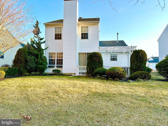 back of property featuring a lawn, a chimney, and a shingled roof