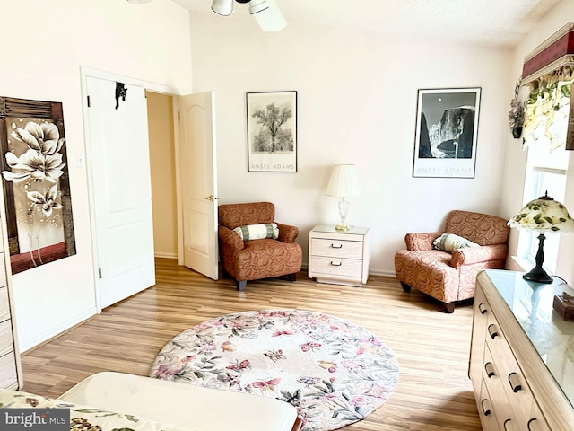 living area featuring lofted ceiling, light wood-style flooring, and a ceiling fan