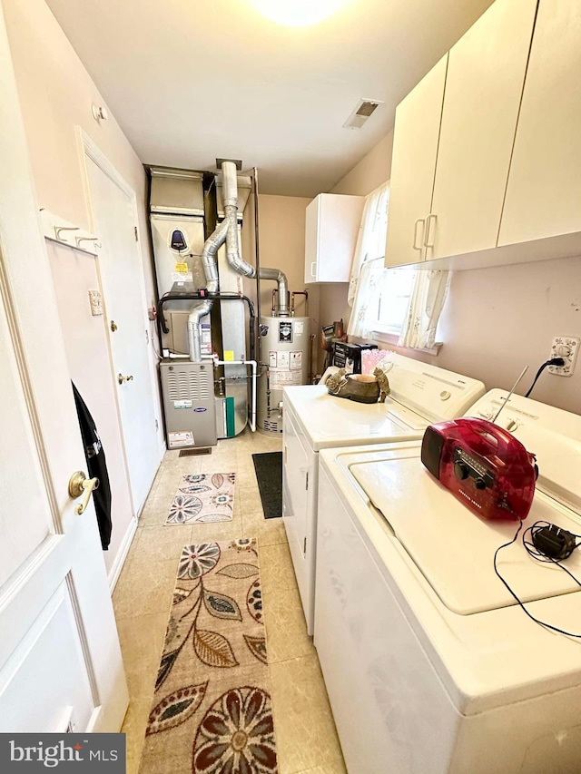 laundry area featuring heating unit, visible vents, cabinet space, water heater, and independent washer and dryer