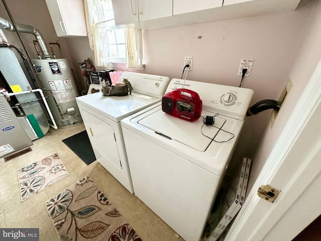 laundry area with water heater, light tile patterned floors, washer and dryer, and cabinet space