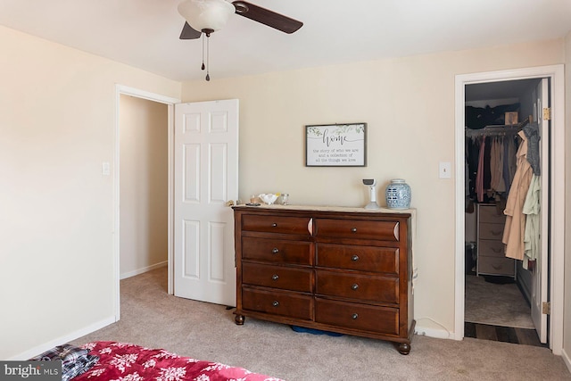 bedroom with baseboards, ceiling fan, a spacious closet, a closet, and light carpet