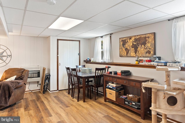 dining area featuring heating unit, a drop ceiling, and light wood finished floors