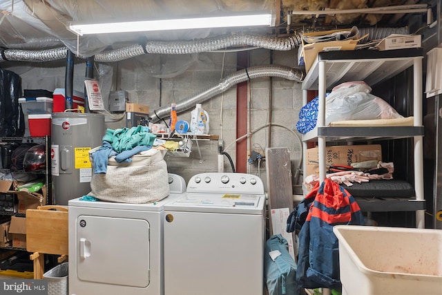 clothes washing area with a sink, laundry area, water heater, and washing machine and clothes dryer