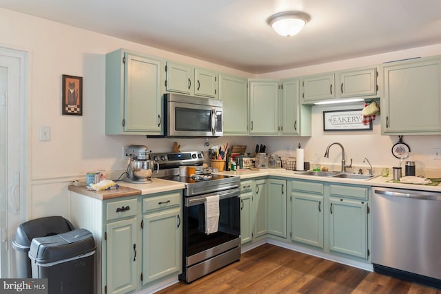 kitchen with appliances with stainless steel finishes, light countertops, dark wood-type flooring, and a sink