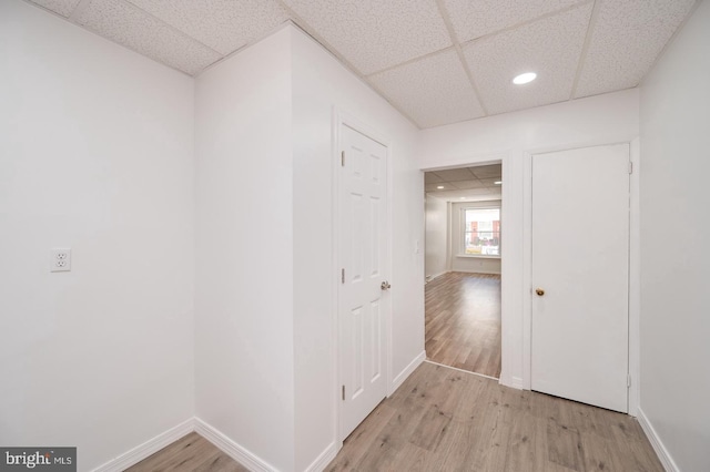 hall featuring recessed lighting, baseboards, a paneled ceiling, and light wood finished floors