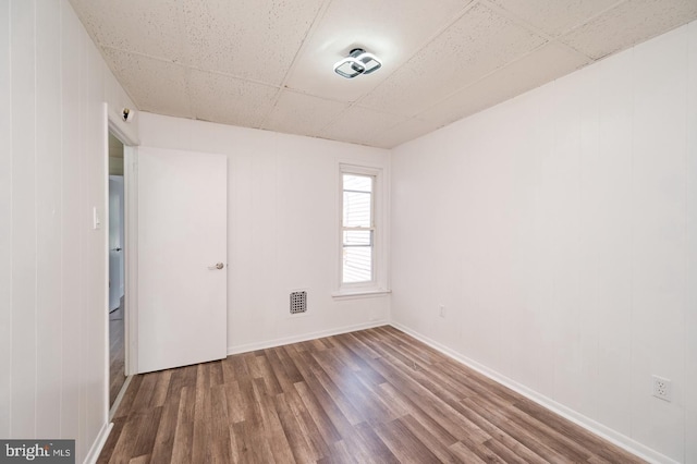 unfurnished room with visible vents, a paneled ceiling, baseboards, and wood finished floors